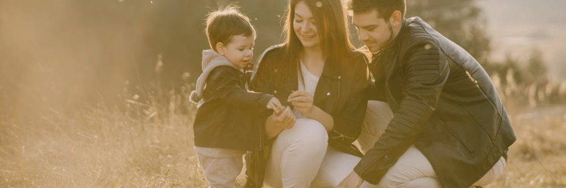 A cheerful family bonding outdoors with a soccer ball, enjoying a sunny day in the grass.